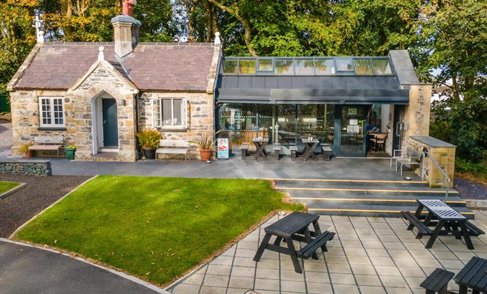 Anglesey Column visitor centre and café with outdoor seating, welcoming entrance, and surrounding greenery on a bright day